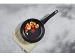 Black frying pan with cooked shrimp, cherry tomatoes, garlic, and rosemary on a grey surface.