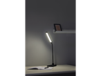 O lampă de birou LED neagră elegantă luminează un caiet și un stilou pe o masă minimalistă.