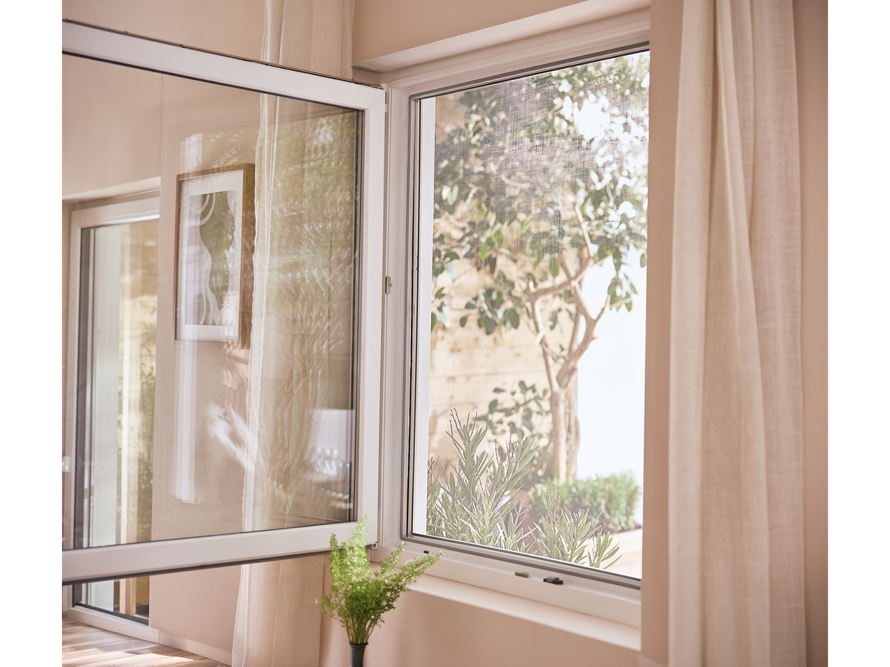 Ανοιχτό παράθυρο με σήτα, που αποκαλύπτει έναν κήπο με δέντρα και φυτά.