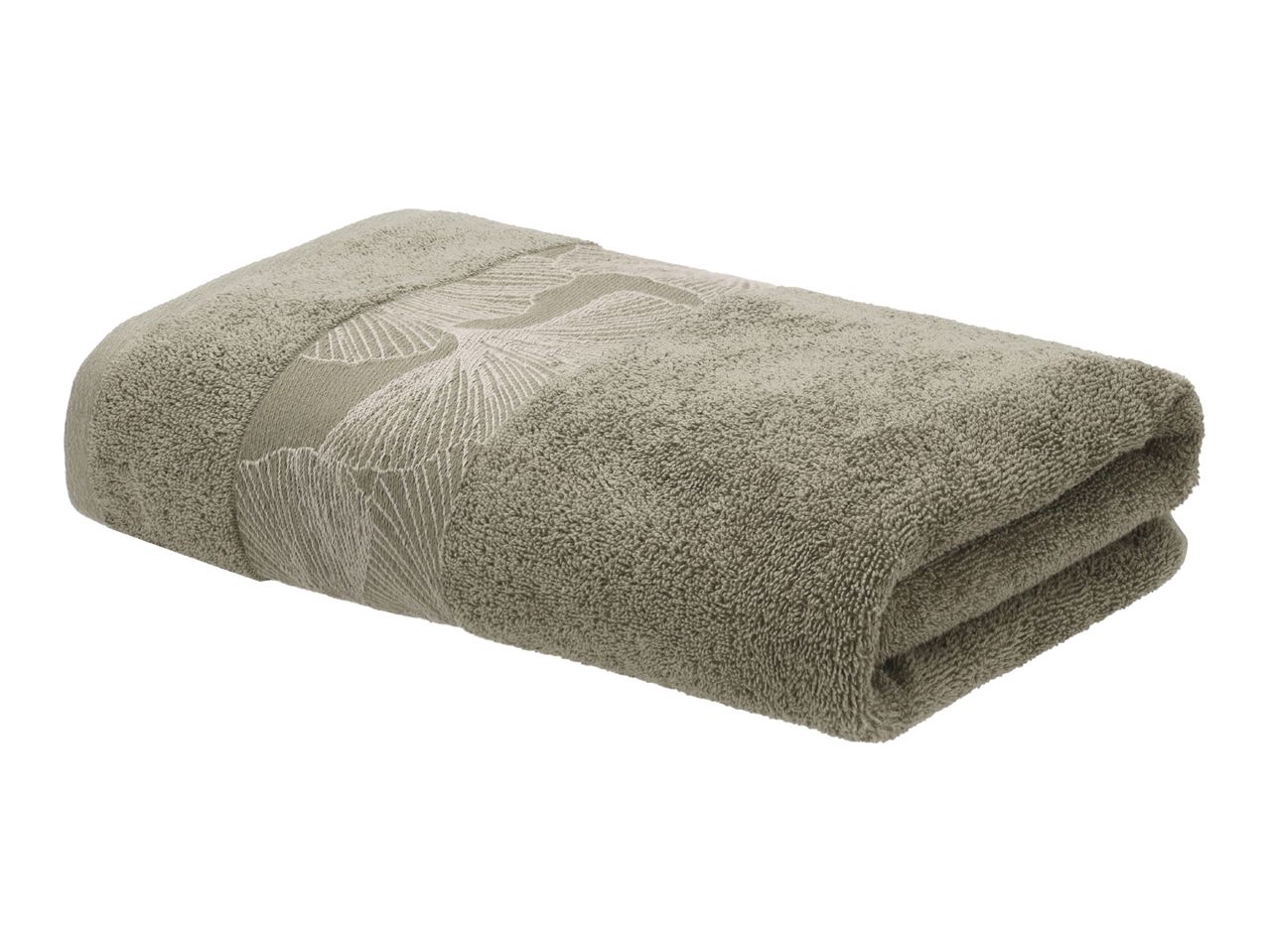 Folded green towel with an embroidered leaf pattern.