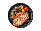 Gegrillte Schweinekoteletts mit gegrilltem Gemüse auf einem schwarzen Teller.
