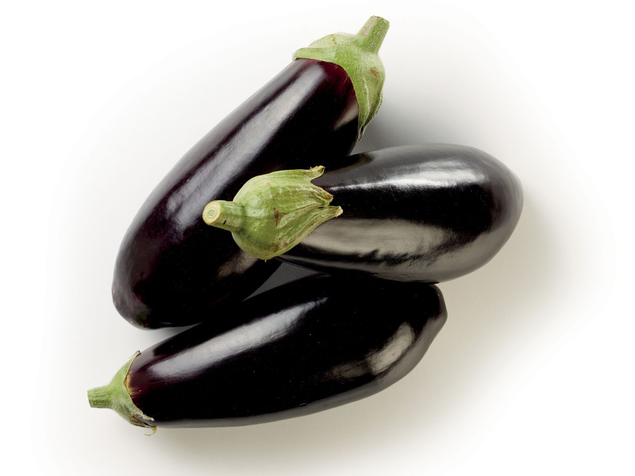 Tre melanzane viola scuro disposte su sfondo bianco.