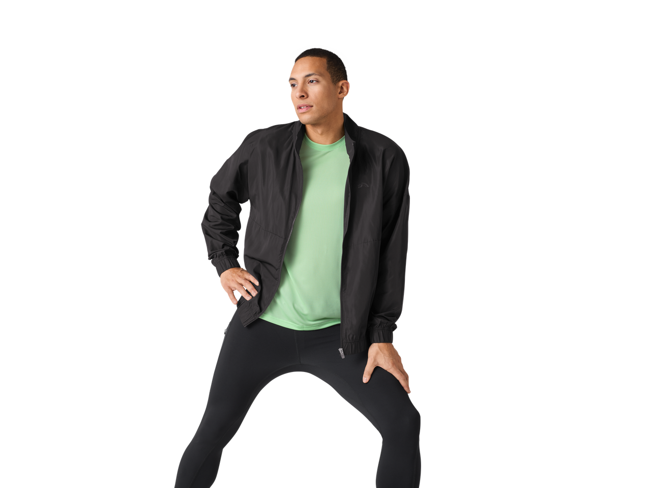 Bărbat în geacă și leggings Reebok negre se întinde.