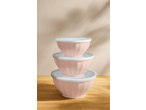 Stack of three pink mixing bowls with white lids on a wooden surface.