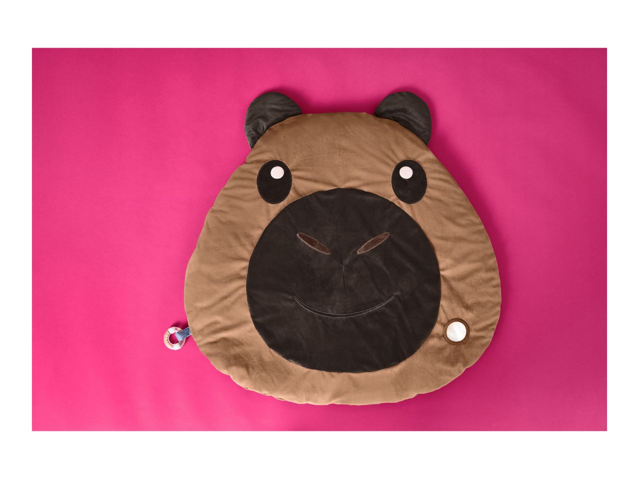 Capybara-shaped baby play mat with a rattle and a mirror on a pink background.