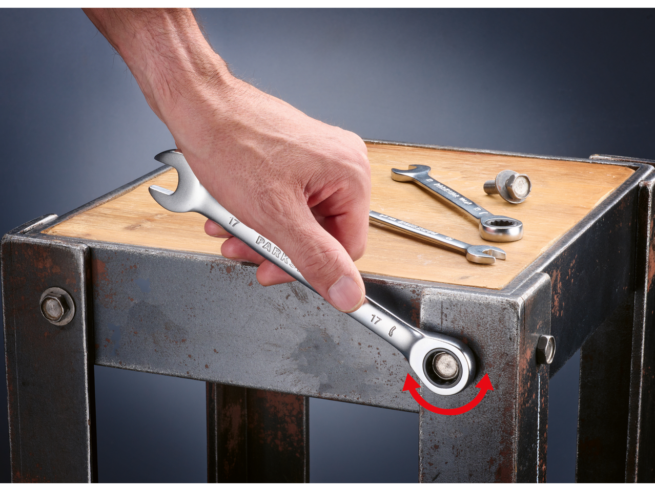 Ръка затяга болт с тресчотен ключ Parkside 17 мм върху метална рамка.