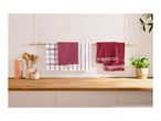 Assorted red and white kitchen towels hanging on a wooden rod above a countertop