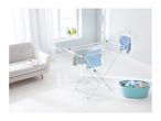 White clothes drying rack with laundry, next to a light grey sofa and a blue laundry basket.