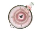 Top-down view of a glass blender jug with a pink base and stainless steel blades.