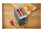 Toaster with two slices of toast, jam, and a butter knife on a wooden table.
