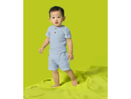 Toddler in light blue short-sleeved top and shorts, standing on a lime green blanket.