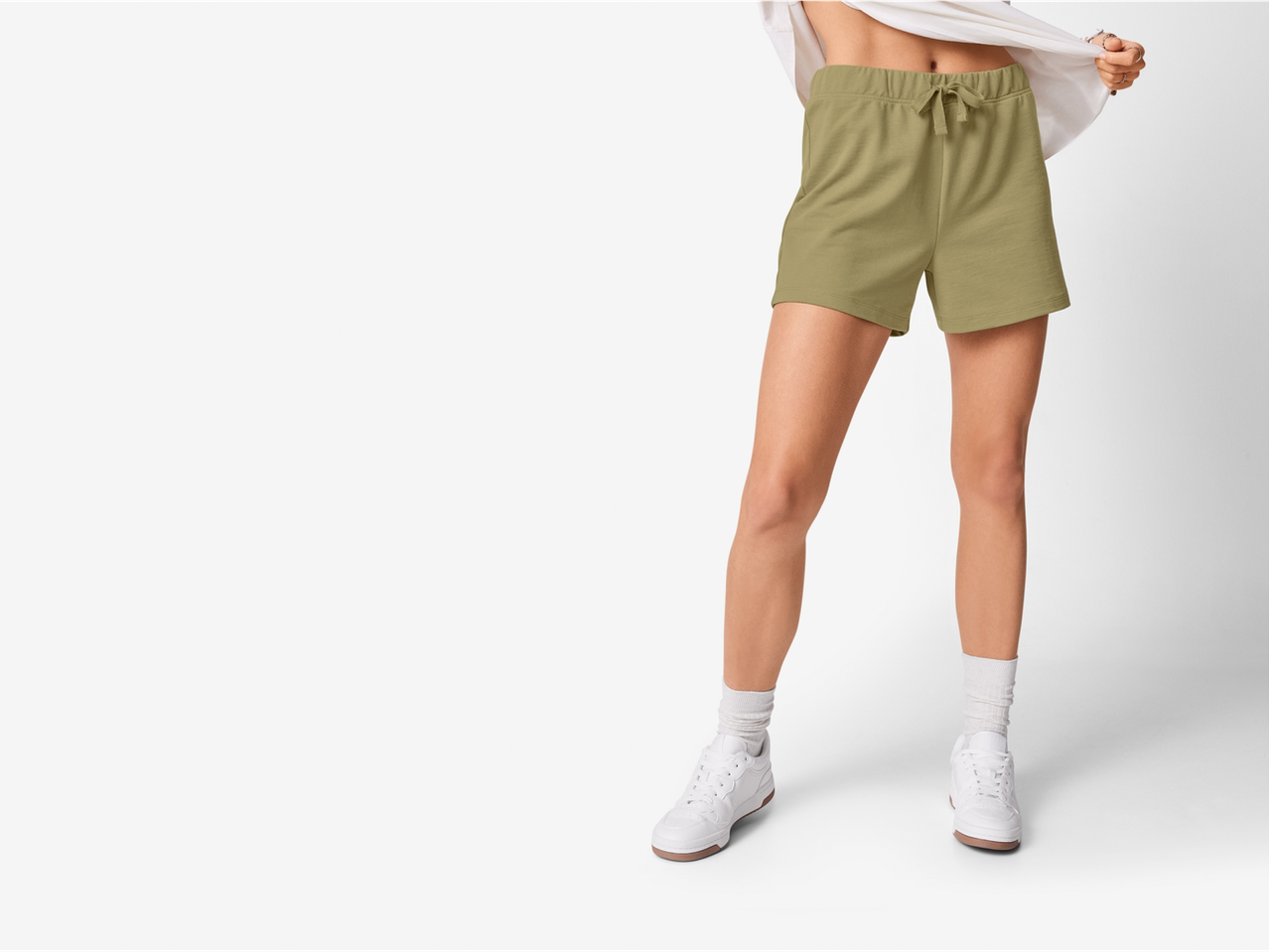 Femeie purtând pantaloni scurți verde-măsliniu și adidași albi.