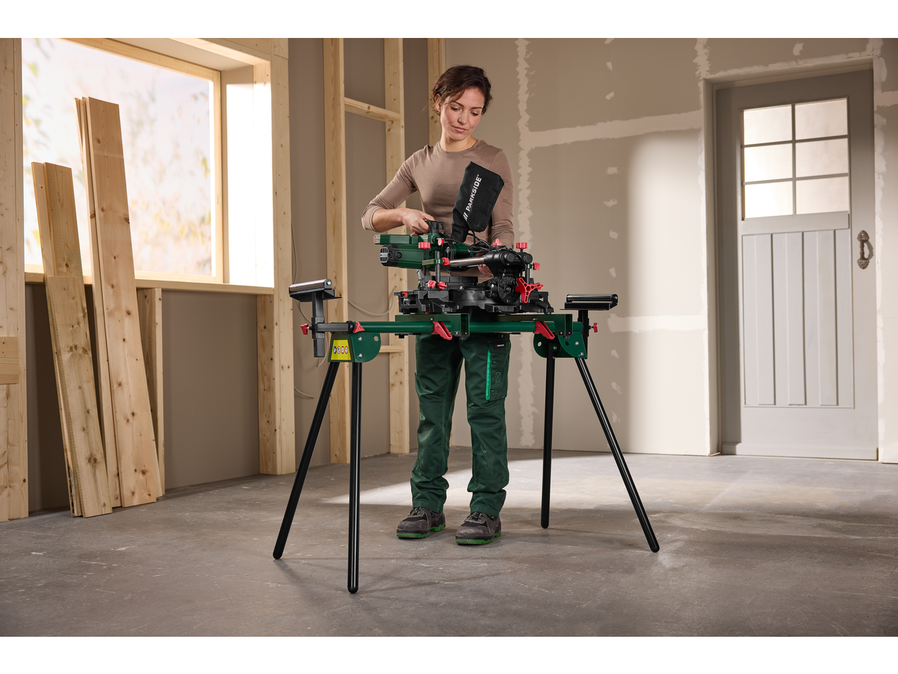 Femeie folosind un suport universal PARKSIDE cu fierăstrău circular într-un șantier.