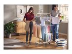 A couple hanging laundry on a multi-tier drying rack in a modern living room.