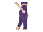 Woman in purple capri leggings with a phone in the side pocket and a matching sports bra.