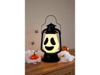 Lanterna di Halloween con faccia da fantasma, ragnatele finte, ragni e zucche decorative.