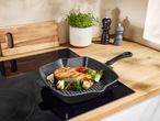 Grilled salmon and vegetables in a cast iron pan on a kitchen counter.