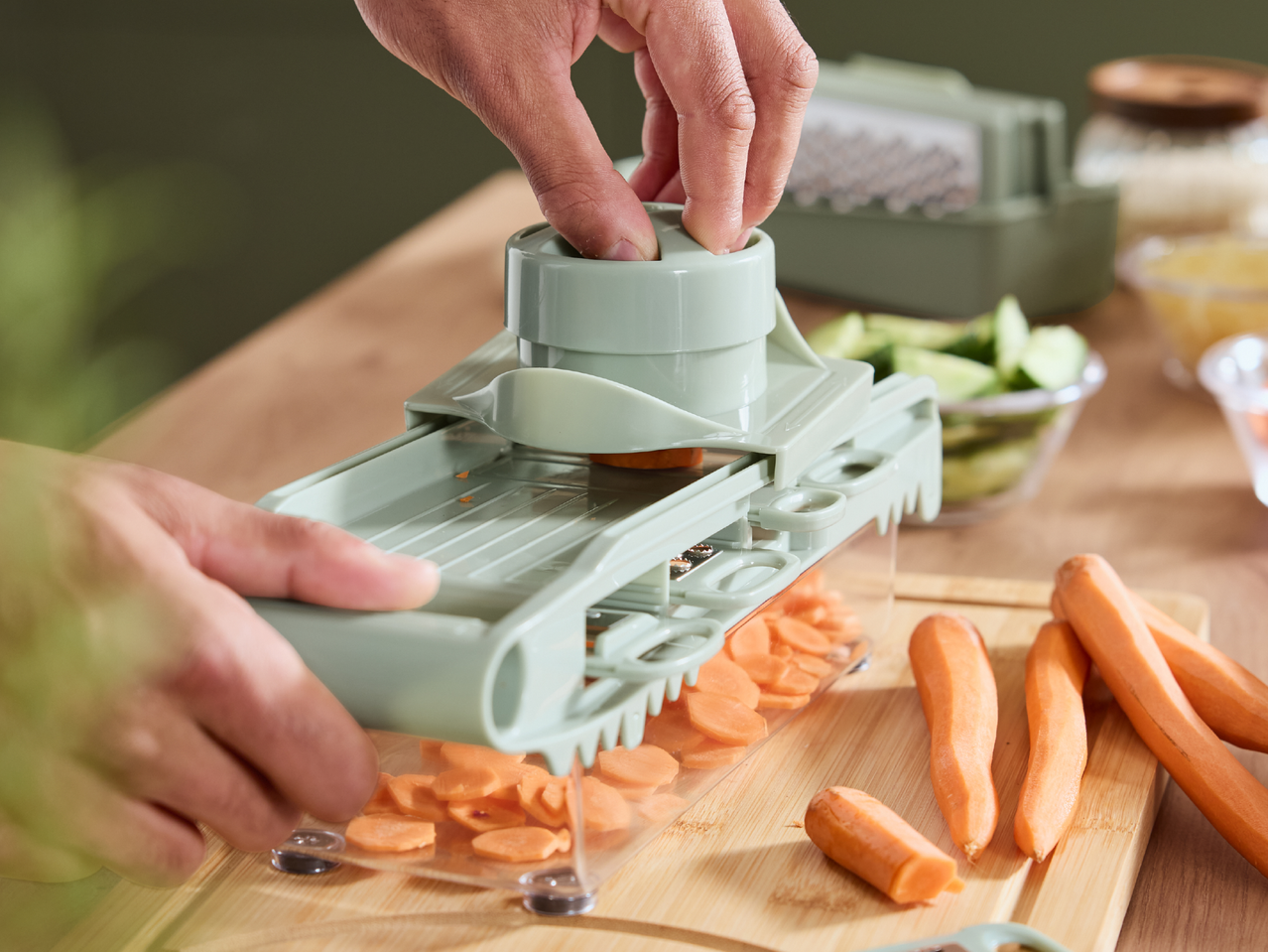 Ръце, използващи резачка за зеленчуци, за да нарежат моркови на кръгчета.