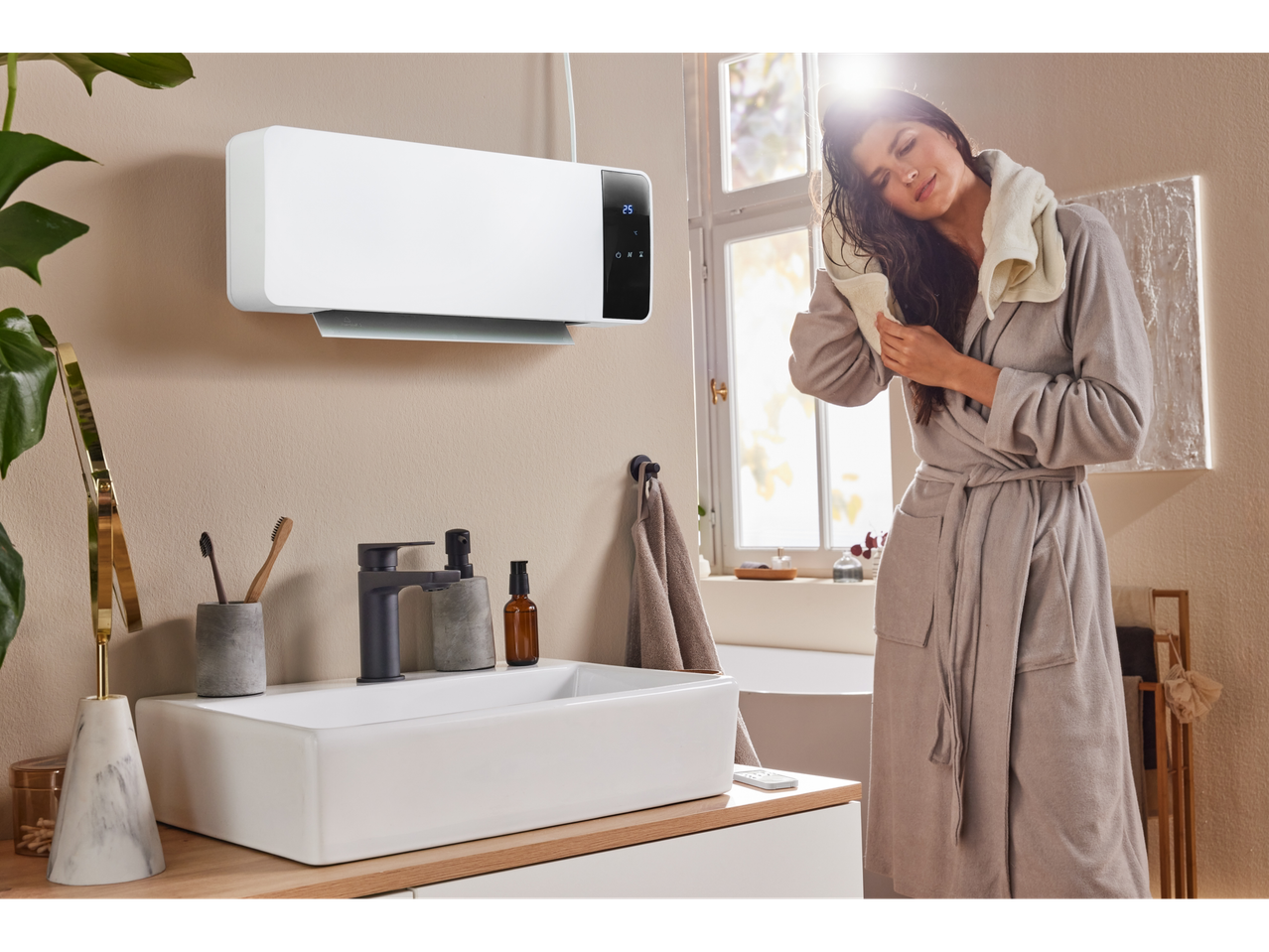 Femme séchant ses cheveux dans une salle de bain avec un chauffage mural céramique Silvercrest®.