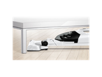 Bosch cordless vacuum cleaner cleaning under a white table on a light wood floor.