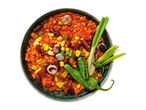 Overhead shot of chili con carne with kidney beans, corn, spring onions, and green chili peppers in a bowl.