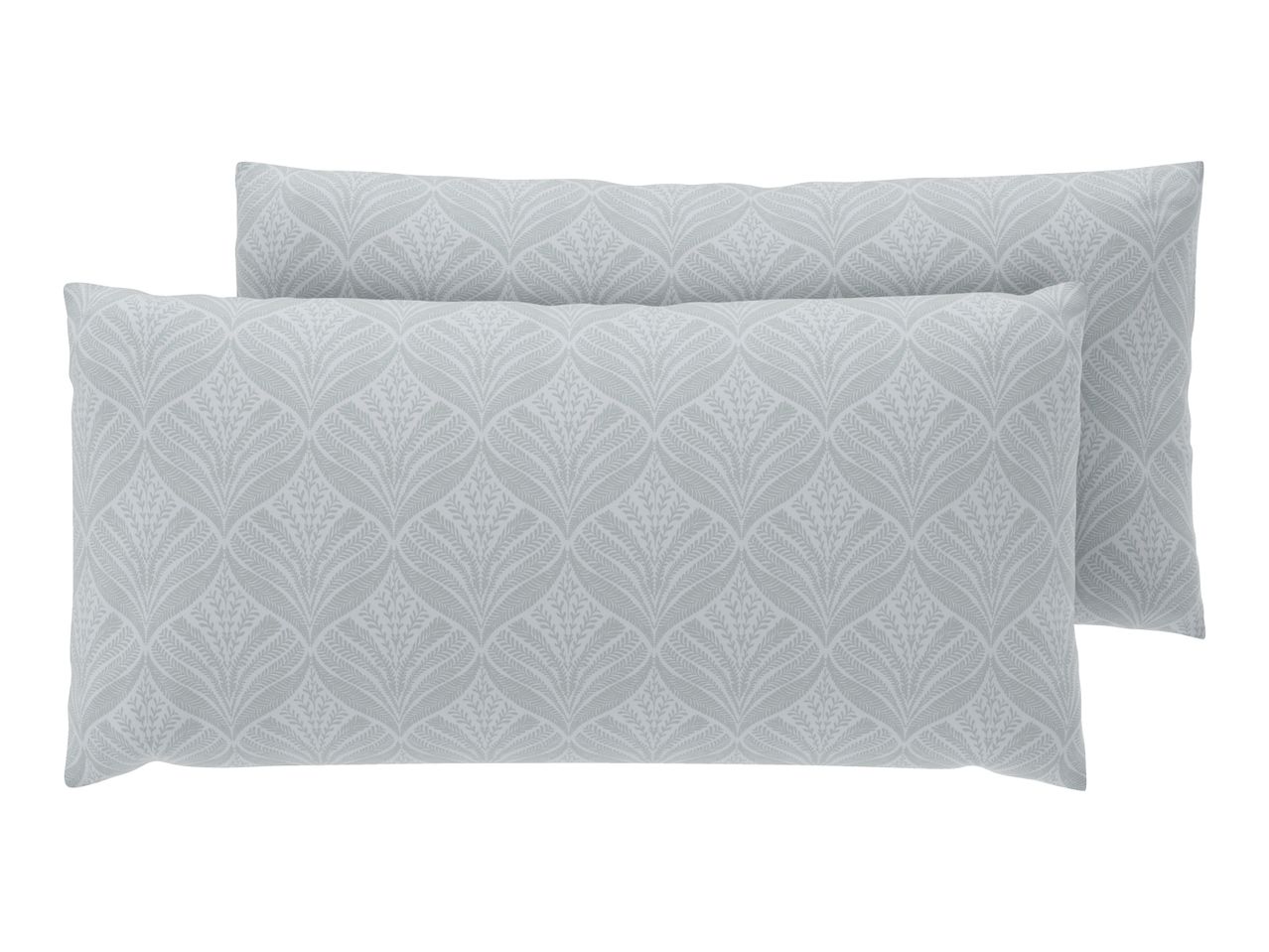 Two light green patterned pillows with a leaf design, one slightly behind the other.
