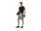Bărbat în tricou negru și pantaloni scurți de ciclism gri, cu cască și încălțăminte.