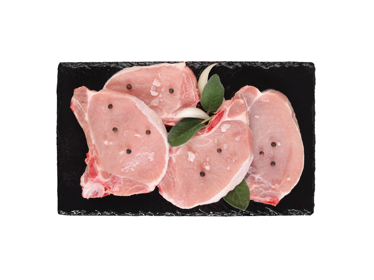 Sveži svinjski kotleti sa začinima i začinskim biljem na crnoj ploči.