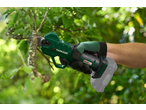 Tesoura de poda elétrica manual a cortar um ramo de árvore, com fundo verde desfocado.