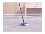A broom sweeping a pile of dust and debris on a light-colored floor.