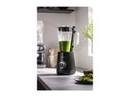 A black blender with green smoothie in a modern kitchen setting.