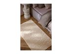 A soft, beige patterned rug on a wooden floor next to a bed.