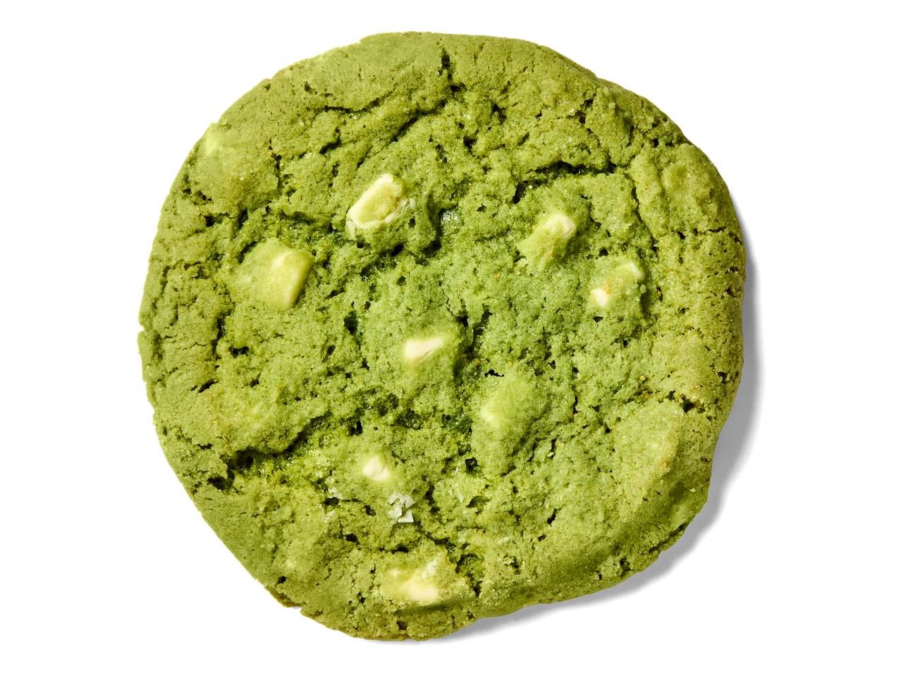 Groene matcha koekje met witte chocoladestukjes op een zwarte achtergrond.