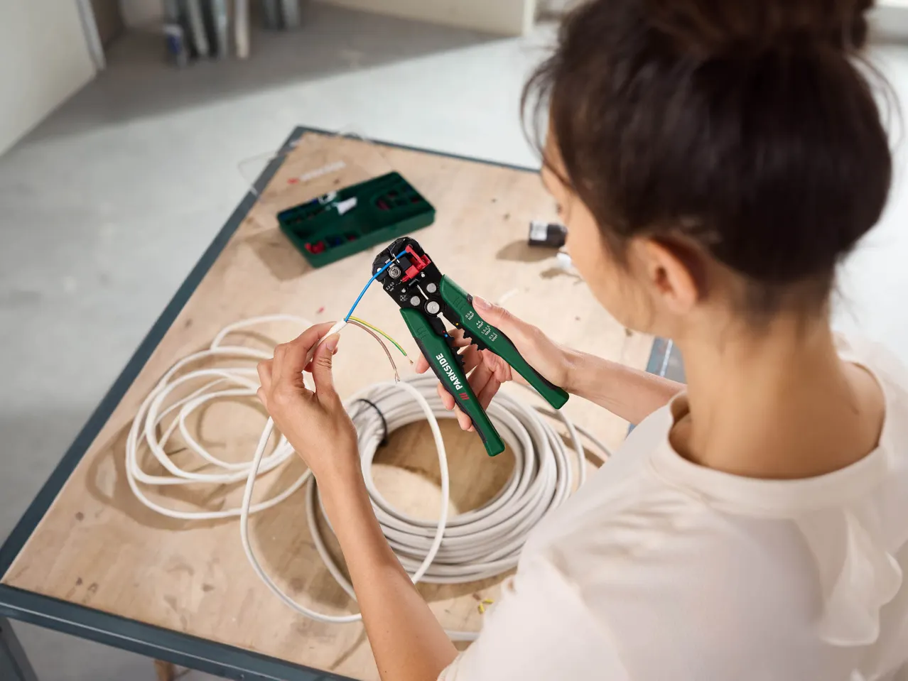 A person using Parkside wire strippers on electrical cables.