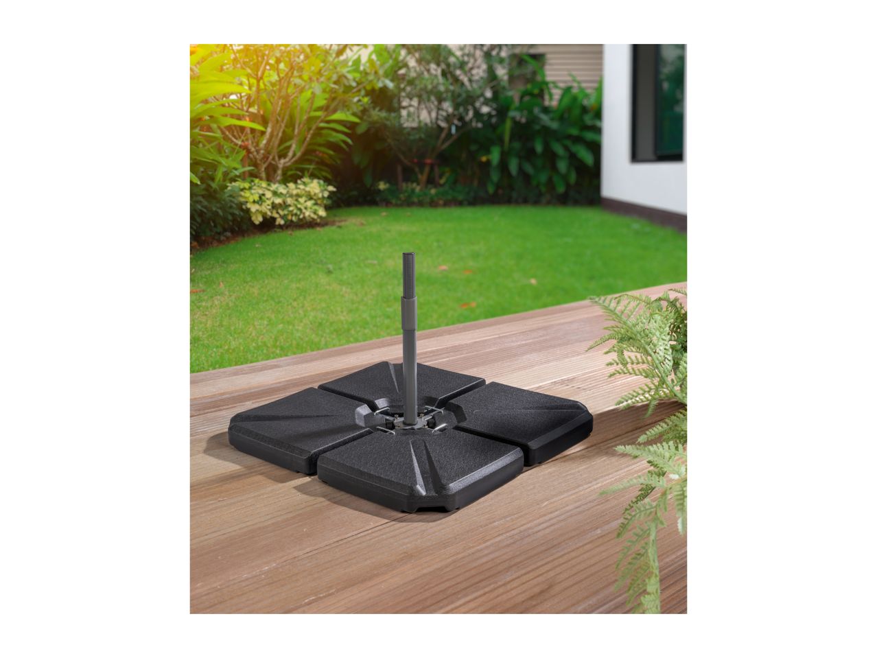 Black parasol base on a wooden deck with a green garden in the background.