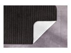 Dark grey bath mat with ribbed texture, corner folded to show non-slip backing on a tiled floor.