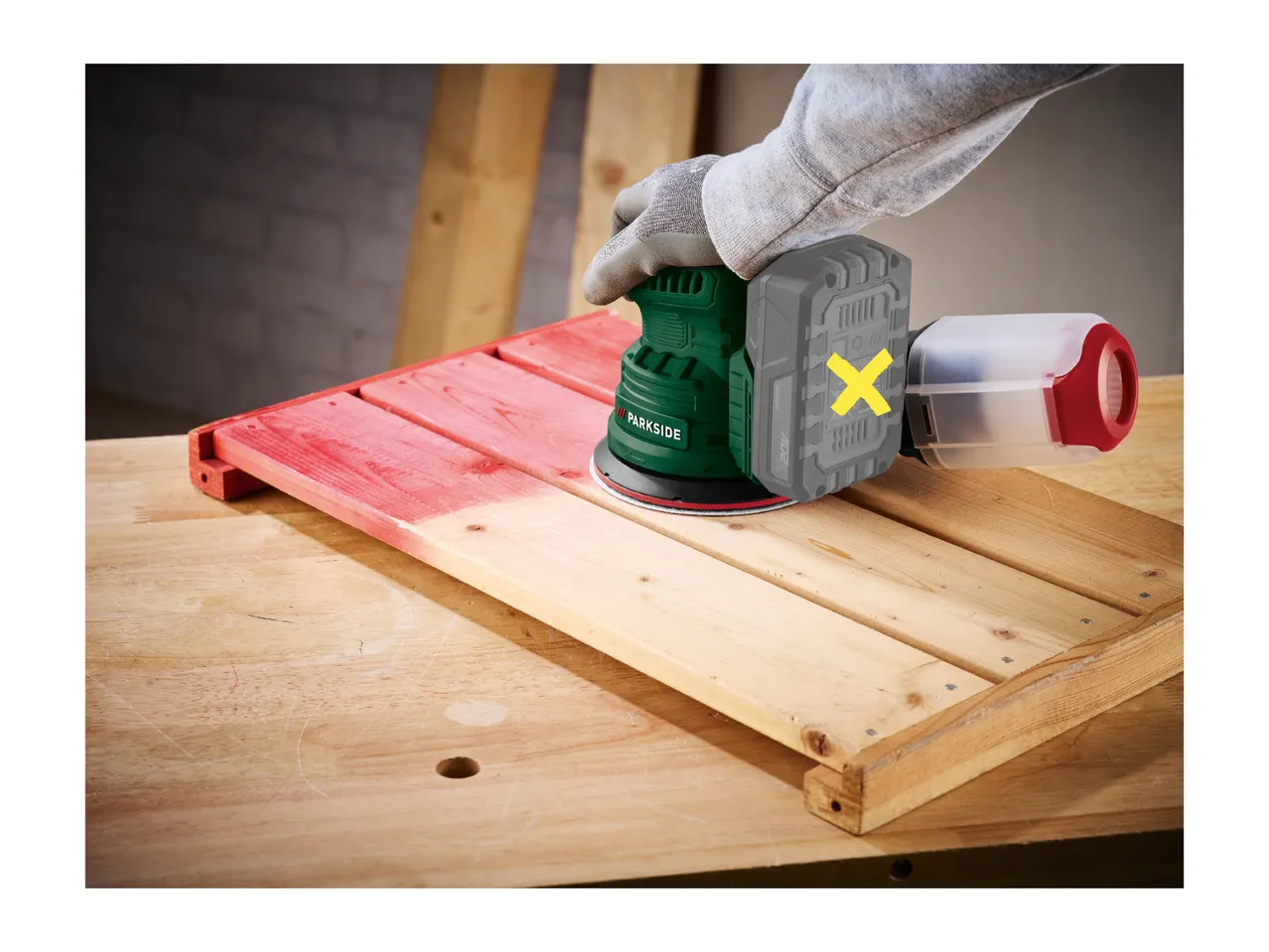 A cordless random orbital sander being used to sand a wooden surface.