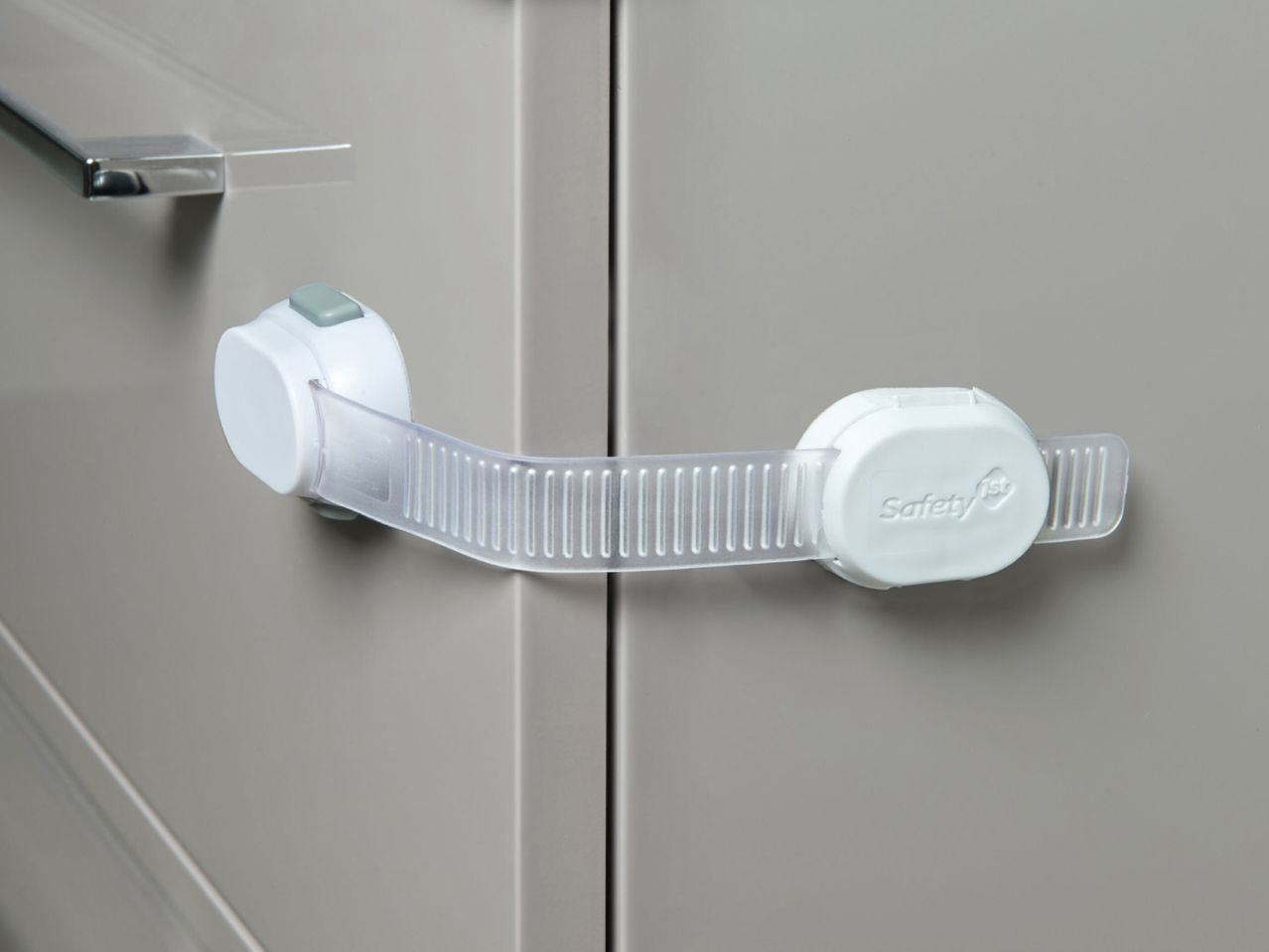 White child safety lock securing two light grey cabinet doors.
