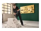 Woman in safety glasses and gloves using a hammer drill on a concrete block.