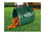 Person holding a green garden waste bag spilling autumn leaves on a lawn.