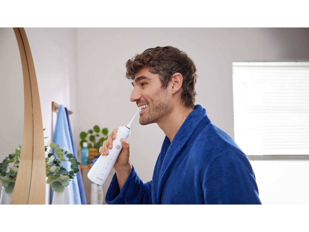 Un uomo usa un idropulsore ricaricabile per la pulizia dei denti.