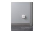 A white smart outlet with USB ports on a light gray wall, above a dark gray floor.