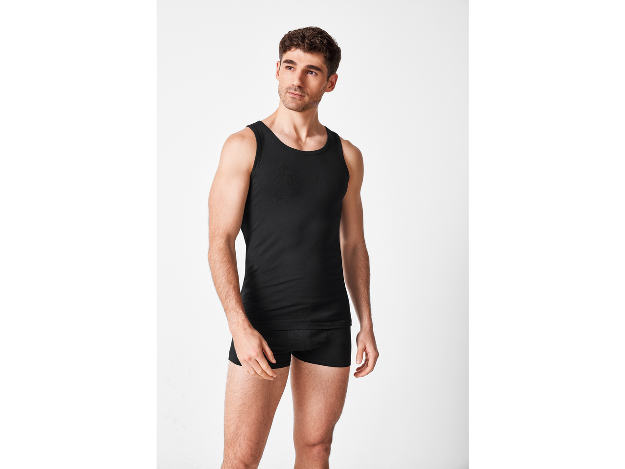 Bărbat modelând un tricou și chiloți negri.