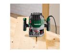 A plunge router on a wooden workbench, with a routed groove in the wood.