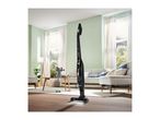 Cordless stick vacuum cleaner in a modern living room with light green walls and wooden floor.