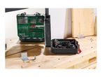 A drill and a drill bit set on a wooden workbench, with various screws and metal brackets.