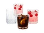 Four patterned glasses, one empty, one with cola and orange, and two with pink raspberry drinks.