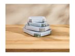 Stack of four collapsible food containers with clear lids on a wooden surface.