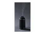 Black ribbed aroma diffuser emitting a gentle mist against a dark grey background