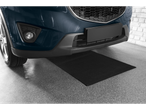 Car parked on a black garage mat, with a brick wall in the background.